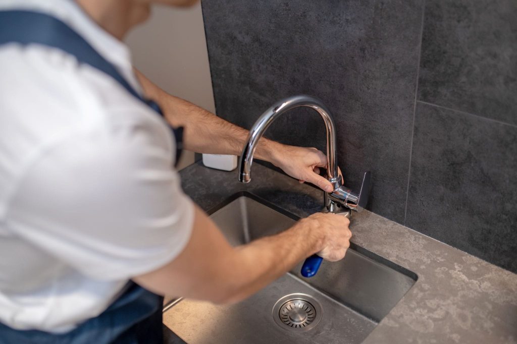 Leaky faucet repair with plumber replacing internal faucet parts.