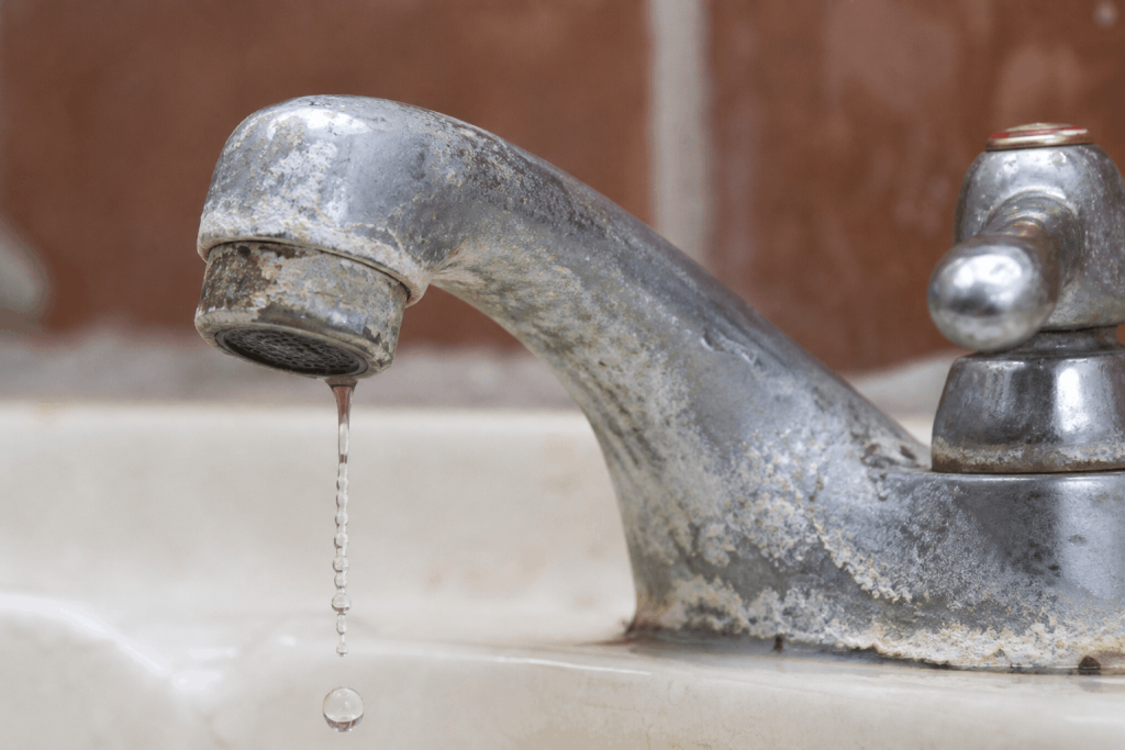 Leaky faucet with visible mineral buildup around spout and base.