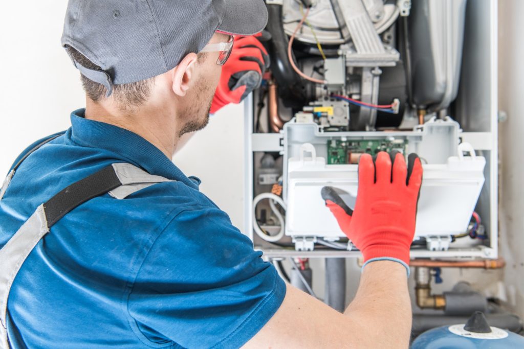 Technician performing heating services on a residential furnace system.